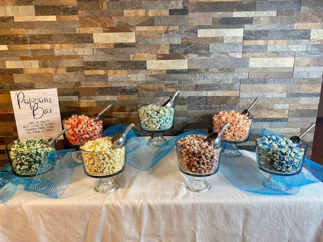 Popcorn bar with assorted colorful flavors displayed in glass bowls, styled by Bri Marie Popcorn.