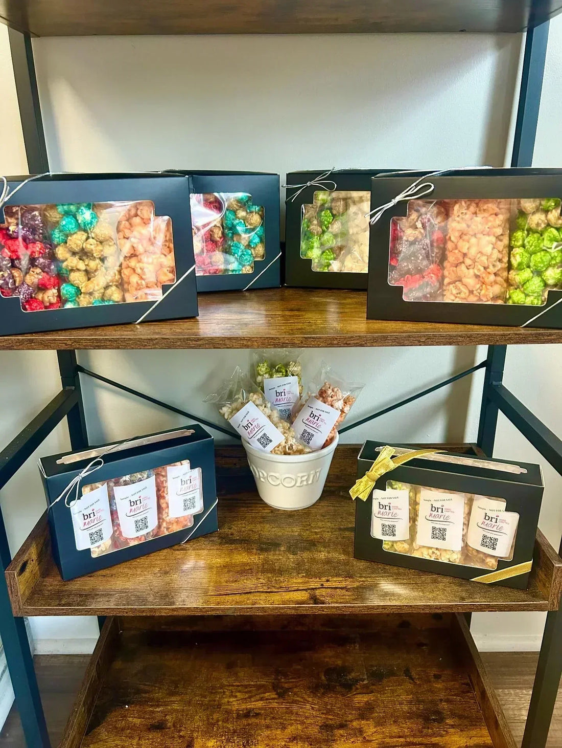 Bri Marie gourmet popcorn gift boxes displayed on wooden shelves with assorted colorful flavors.