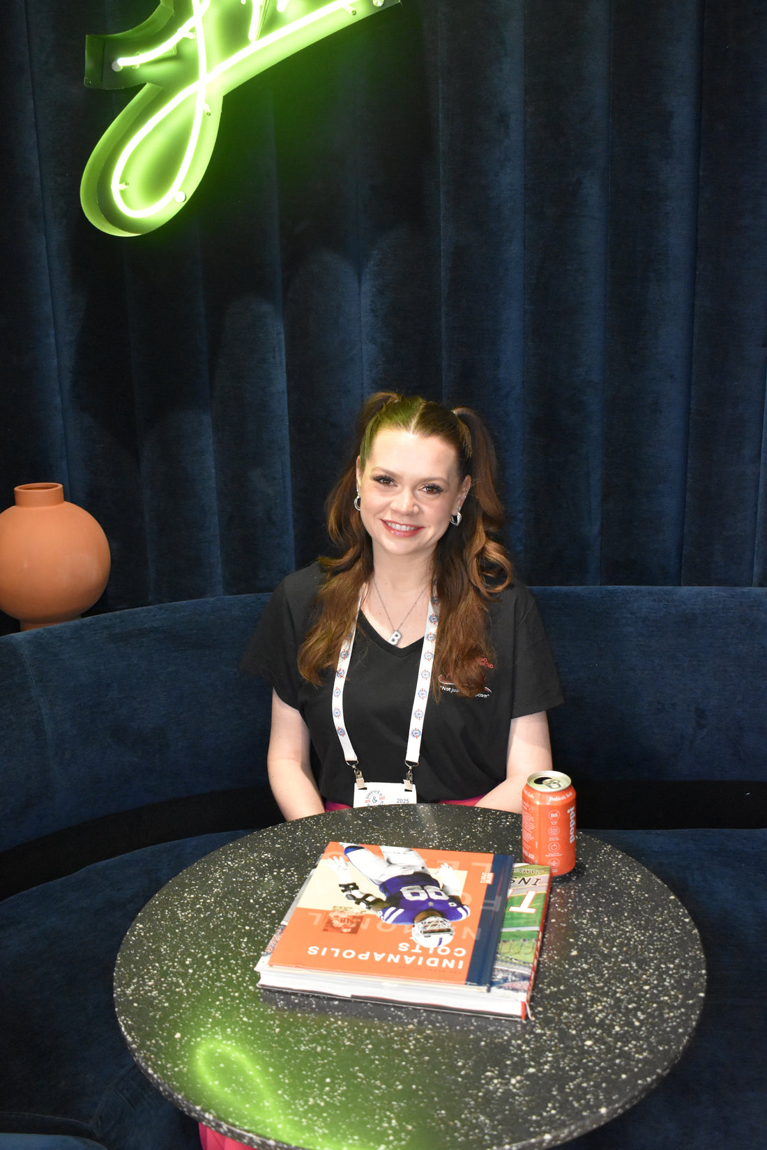 Brianna, founder of Bri Marie Gourmet Popcorn, seated at a table with a book and a drink in a cozy lounge setting, reflecting on her entrepreneurial journey.