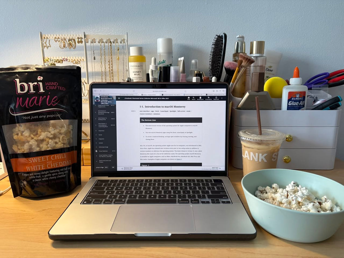 Bri Marie popcorn in a bowl and bag placed on a desk with a laptop and coffee for an afternoon snack break.